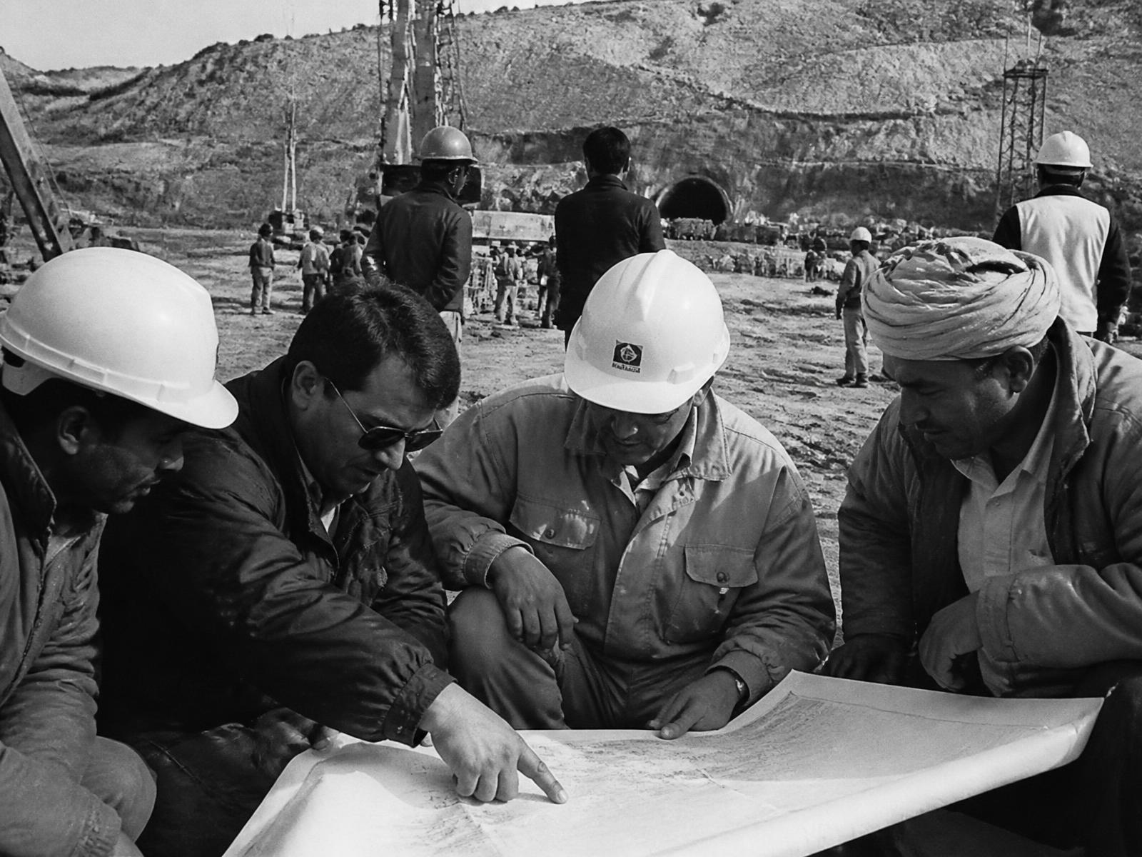 Archival photograph of engineers reviewing plans on a construction site